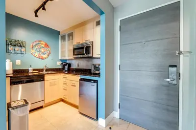 a kitchen with stainless steel appliances and a gray door at Modern Ft Lauderdale Condo about 7 Mi to Airport! in Fort Lauderdale