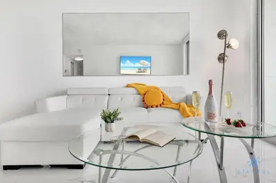 a white living room with a white couch and a glass table at Special Offer - Balcony - Beachfront Condo - Gym in Hollywood