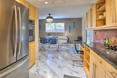 a kitchen with a stainless steel refrigerator and a table at Wilton Manors Home with Pool about 4 Mi to Beach! in Fort Lauderdale