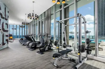 a gym with a row of treadmills and machines at Modern Beachfront Condo with Stunning Ocean View in Hollywood