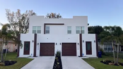 a white house with two garage doors at Luxe Fort Lauderdale in Fort Lauderdale