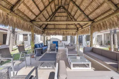 an outdoor patio with chairs and tables and a straw roof at Walnut By The Sea in Hollywood