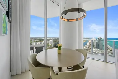 a dining room with a table and chairs and a large window at Beautiful Beachfront Penthouse in Hollywood