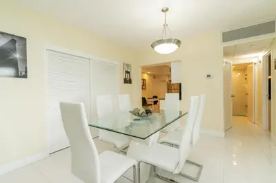 a dining room with a glass table and white chairs at The Tides apartment Go Holiday Home 5th floor in Hollywood