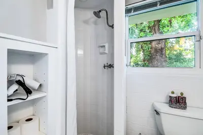 a white bathroom with a toilet and a window at *Victoria Park Pool Home- close to beach/Las Olas* in Fort Lauderdale