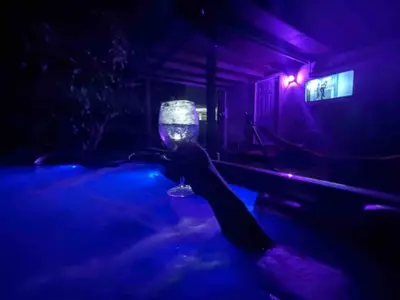 a person is holding a wine glass in a dark room at “La Casita” Beautiful home in the heart of Miami ! in Miami