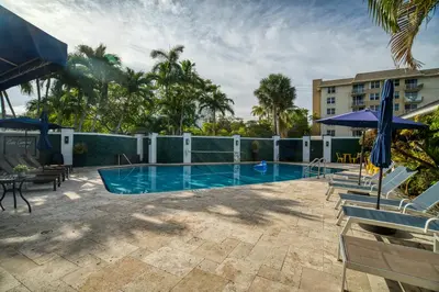 a pool with chairs and umbrellas next to a building at Casa Cordova Apartments By Lowkl in Fort Lauderdale