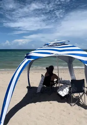 a woman sitting under an umbrella on the beach at Lovely beaches ocean & city view in Miami Beach