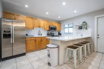 a kitchen with wooden cabinets and a stainless steel refrigerator at Renovated 2 BD Home w/ Private Parking, Gallery & W/D in Miami