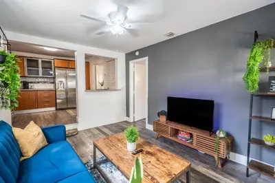 a living room with a blue couch and a tv at 2 BD Home w/ Private Parking, Private Yard & W/D in Miami