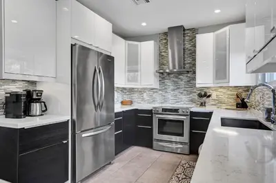 a kitchen with white cabinets and a stainless steel refrigerator at Victoria Park Overlook in Fort Lauderdale
