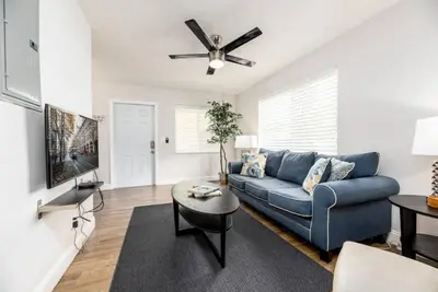 a living room with a blue couch and a ceiling fan at The Guesthouse 1 - Wilton Manors in Fort Lauderdale