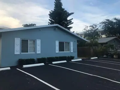 a parking lot with a blue building and a tree at The Guesthouse 2 - Wilton Manors in Fort Lauderdale