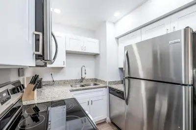 a kitchen with a stainless steel refrigerator and white cabinets at The Guesthouse 2 - Wilton Manors in Fort Lauderdale