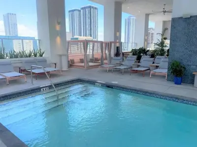 a swimming pool in a hotel with chairs and tables at Modern 1 Bed Condo across from Bayside in Downtown in Miami