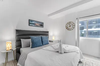 a bedroom with two beds and a clock on the wall at Lovely Unit Mins from Wynwood with Free Parking in Miami