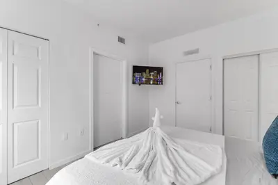 a white bedroom with a white bed and a picture on the wall at Lovely Unit Mins from Wynwood with Free Parking in Miami