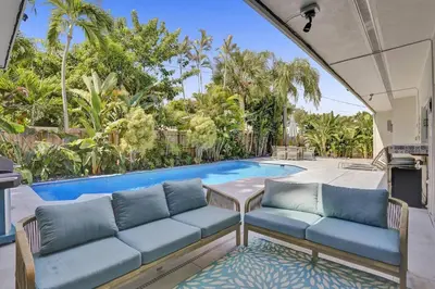 a living room with a couch and a swimming pool at Brand New! Heated Pool, Golf Cart, Next to Beach in Fort Lauderdale