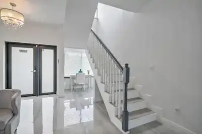 a white staircase in a living room with a chandelier at New Townhome near Wilton/Las Olas/Beach in Fort Lauderdale