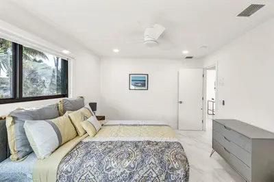 a bedroom with a large bed and a large window at Sandals Beach Cottage in Fort Lauderdale
