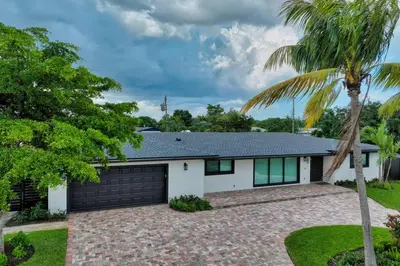 a house with a garage and a palm tree at Sandals Beach Cottage in Fort Lauderdale