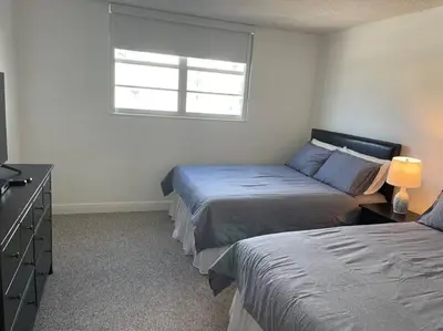 a bedroom with two beds and a dresser and a window at Ocean reserve 702 - STR 2315 in Miami Beach
