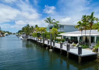 a dock next to a river with houses and palm trees at Casa Flamingo Intracoastal Front with Heated Pool in Fort Lauderdale