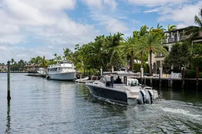 two boats are docked in a river with palm trees at Casa Flamingo Intracoastal Front with Heated Pool in Fort Lauderdale
