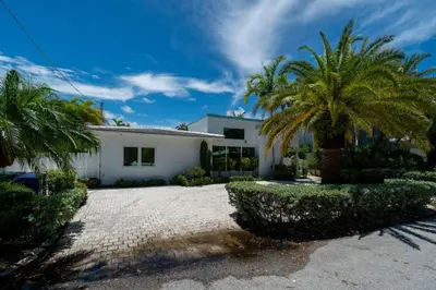 a white house with palm trees in front of it at Casa Flamingo Intracoastal Front with Heated Pool in Fort Lauderdale