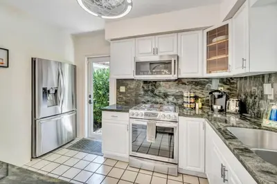 a kitchen with white cabinets and a stainless steel refrigerator at Victoria Park Oasis with Heated Pool and More in Fort Lauderdale