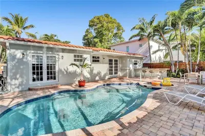 a swimming pool in front of a house at Chic Victoria Park Villa with Heated Pool and Spa in Fort Lauderdale