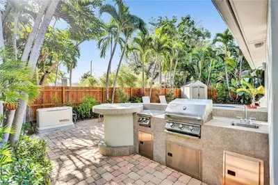 an outdoor kitchen with a grill and a patio at Chic Victoria Park Villa with Heated Pool and Spa in Fort Lauderdale