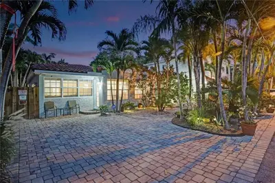 a house with palm trees and a brick driveway at Chic Victoria Park Villa with Heated Pool and Spa in Fort Lauderdale