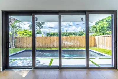 an empty room with sliding doors looking out at a swimming pool at Lux Villa with Pool, Wynwood House by RoveTravel in Miami
