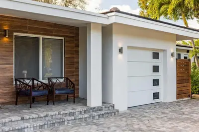 a detached garage with two chairs on a patio at Olas Villa by Rove Travel - Home with Heated Pool in Fort Lauderdale