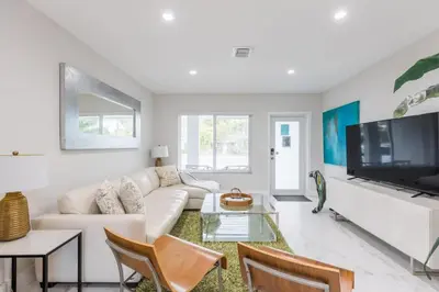 a living room with a white couch and a tv at Olas Villa by Rove Travel - Home with Heated Pool in Fort Lauderdale
