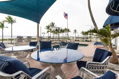 a patio with tables and chairs and the beach at Oceana Blue / Beach Front / Pool / Bar / Relax in Fort Lauderdale