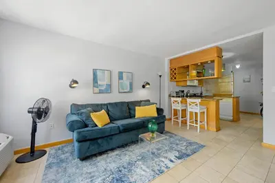a living room with a blue couch and a kitchen at Cozy studio, walk to the beach, restaurants, bars in Miami Beach