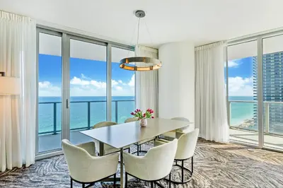 a dining room with a table and chairs and large windows at Ocean Front Paradiiise 3 Bedroom by Zen in Hollywood