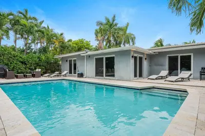 a swimming pool in front of a house with palm trees at Modern 4BR Villa with Pool - Outdoor amenities - WFH in Fort Lauderdale