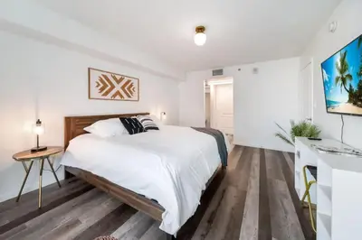 a white bedroom with a large bed and wooden floors at Penthouse APT w Private Balcony King Bed Parking in Miami