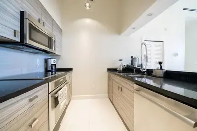 a kitchen with wooden cabinets and a black counter top at Ocean view Work from Home Balcony Parking Pool in Miami