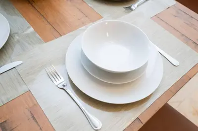 a table with two white plates and a fork and knife at 2Bed 2 Bath Airbnb Friendly building with Pool, Hot Tub, and Gym in Miami