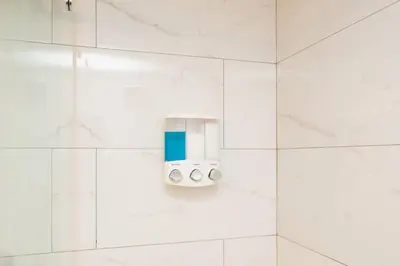 a white bathroom with a soap dispenser on the wall at 2Bed 2 Bath Airbnb Friendly building with Pool, Hot Tub, and Gym in Miami