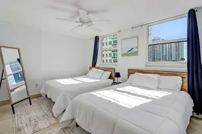 two beds in a room with two windows at 2 Bedroom, 2 Bathroom plus Den Brickell Condo Pool, Hot Tub, and Gym in Miami