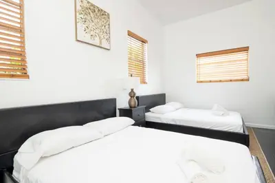 two beds in a room with white walls and windows at Modern 5 Bedroom Miami Home 15 Min to the Beach in Miami