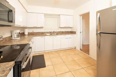 a kitchen with white cabinets and a stainless steel refrigerator at Modern 5 Bedroom Miami Home 15 Min to the Beach in Miami