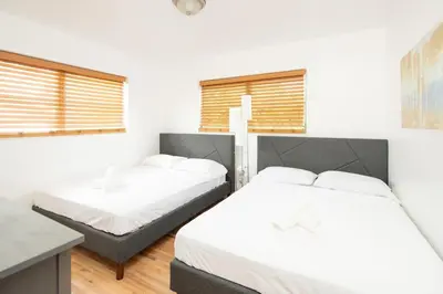 two beds in a room with white walls and windows at Modern 5 Bedroom Miami Home 15 Min to the Beach in Miami