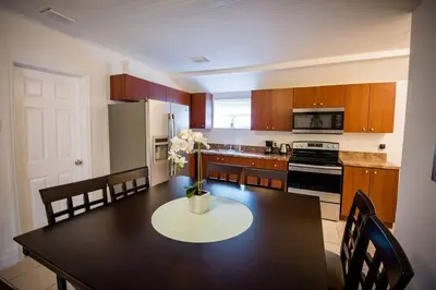 a kitchen with a black table and a kitchen with a refrigerator at 3 Bedroom Miami Home 15 Minutes to the Beach in Miami