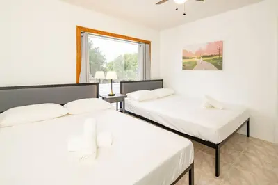two beds in a white room with a window at Waterfront 2-Story Villa with Heated Pool in Pembroke Pines